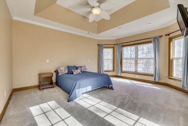 carpeted bedroom featuring a raised ceiling, multiple windows, baseboards, and ornamental molding