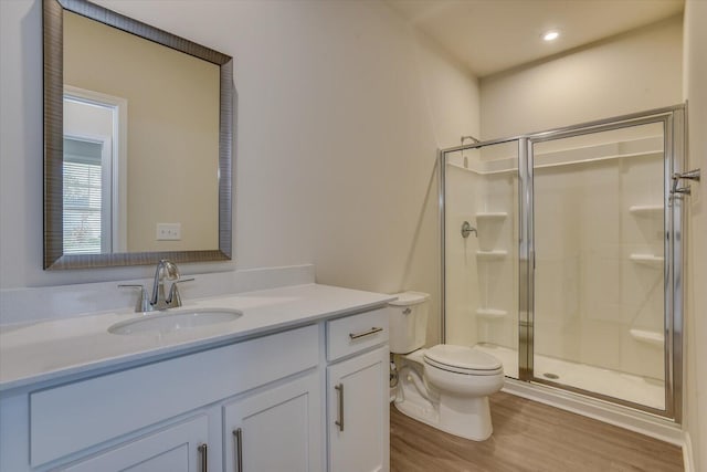 bathroom featuring hardwood / wood-style floors, vanity, toilet, and a shower with door