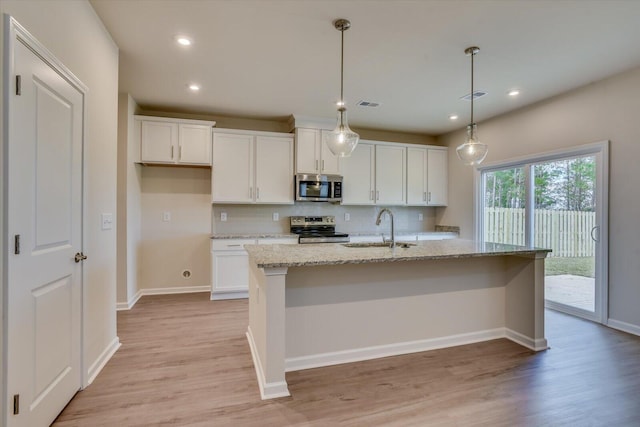 kitchen featuring sink, hanging light fixtures, an island with sink, white cabinets, and appliances with stainless steel finishes