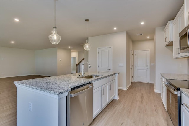 kitchen with sink, white cabinetry, stainless steel appliances, and an island with sink