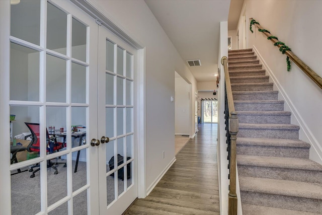 stairs with hardwood / wood-style floors and french doors