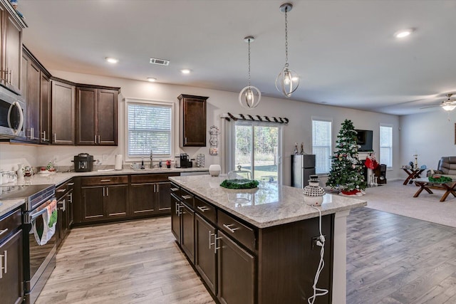 kitchen with decorative light fixtures, dark brown cabinetry, stainless steel appliances, and a kitchen island