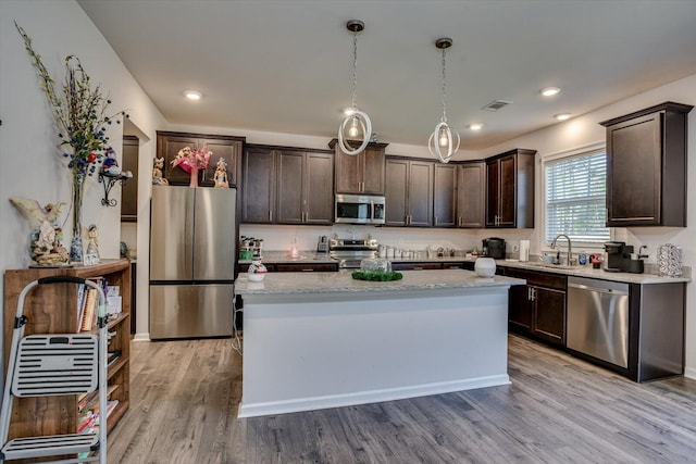 kitchen featuring sink, a center island, stainless steel appliances, light hardwood / wood-style flooring, and decorative light fixtures