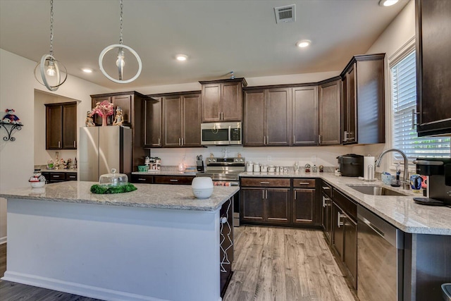 kitchen featuring a center island, sink, light hardwood / wood-style flooring, decorative light fixtures, and stainless steel appliances