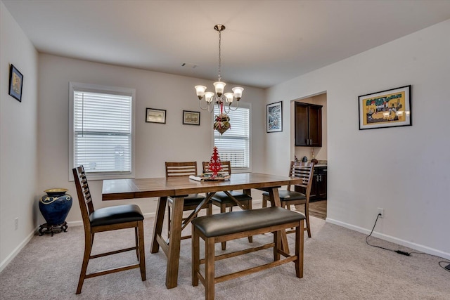 carpeted dining space featuring plenty of natural light and an inviting chandelier