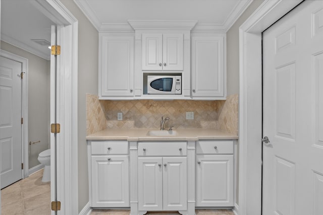 3997 Hammonds Fry, Evans, GA 30809 - kitchen featuring white microwave, light countertops, crown molding, white cabinetry, and tasteful backsplash
