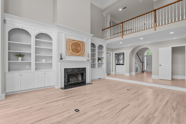 3997 Hammonds Fry, Evans, GA 30809 - unfurnished living room featuring a high ceiling, crown molding, a premium fireplace, light wood-style flooring, and arched walkways