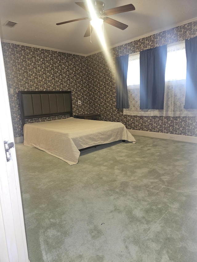 carpeted bedroom with wallpapered walls, visible vents, ornamental molding, and ceiling fan