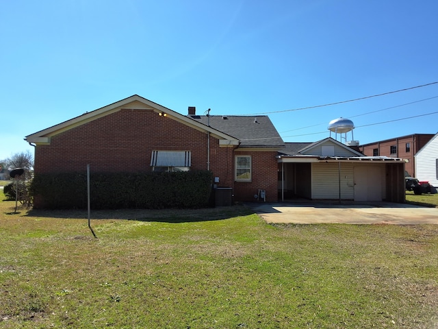 back of house featuring brick siding, a lawn, and a patio