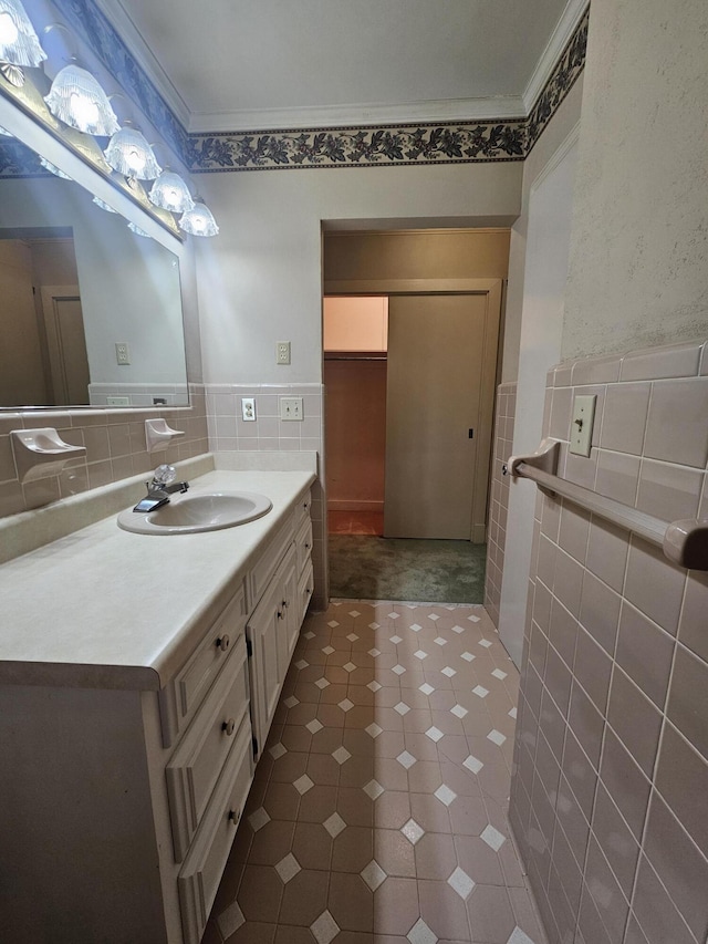 bathroom with wainscoting, crown molding, tile walls, and vanity