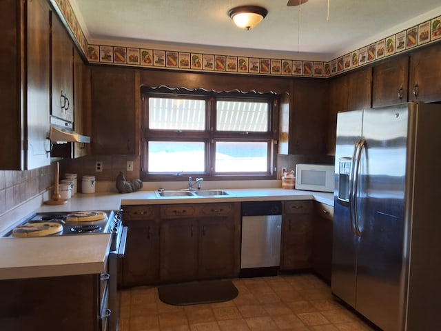 kitchen featuring under cabinet range hood, stainless steel appliances, a sink, dark brown cabinets, and light countertops