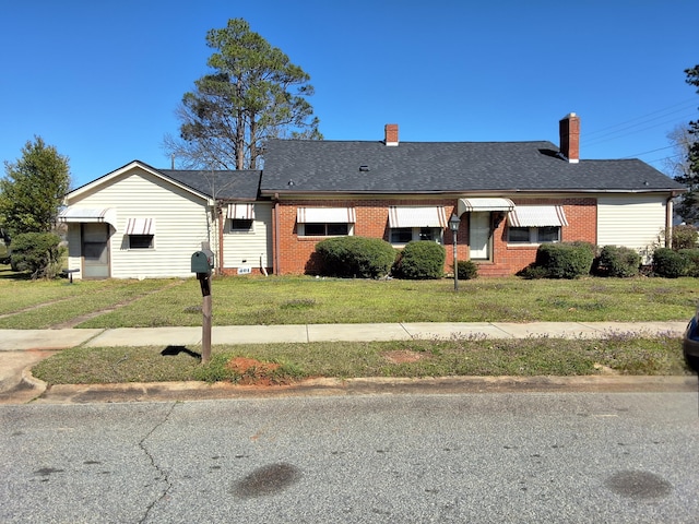 ranch-style house featuring brick siding, roof with shingles, and a front yard