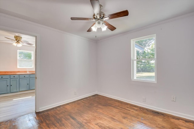 spare room with dark wood-type flooring, ceiling fan, and crown molding