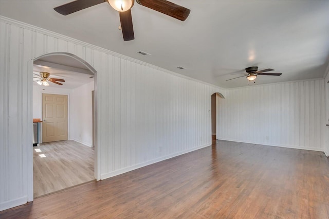 empty room with hardwood / wood-style flooring, ceiling fan, and crown molding