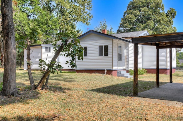 back of property with a yard and a carport