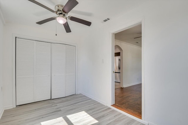 unfurnished bedroom with stainless steel fridge, a closet, light hardwood / wood-style flooring, and ceiling fan