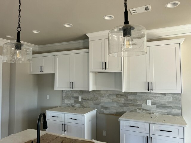 kitchen with ornamental molding, visible vents, backsplash, and white cabinetry