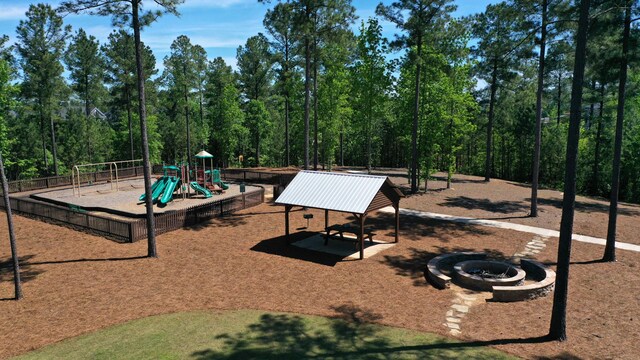 community jungle gym featuring an outdoor fire pit and fence