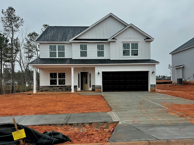 view of front of house with a porch, a shingled roof, concrete driveway, an attached garage, and board and batten siding