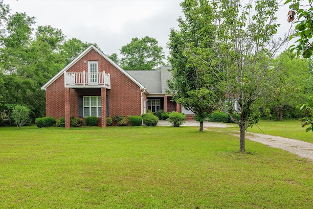 view of front of house with driveway, a front yard, brick siding, and a balcony