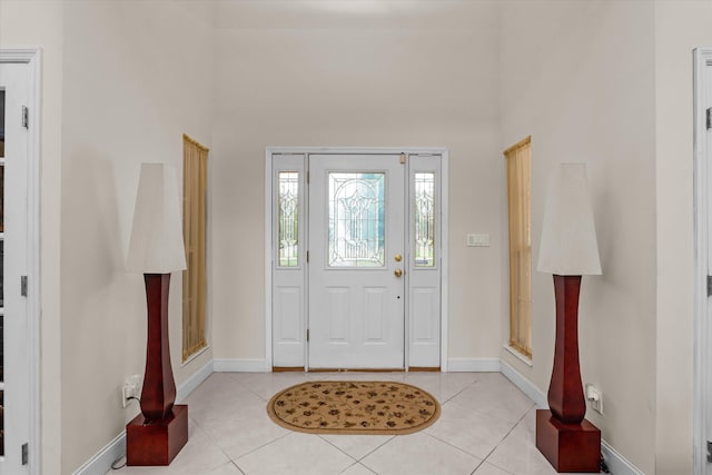 entrance foyer with a towering ceiling, baseboards, and light tile patterned flooring
