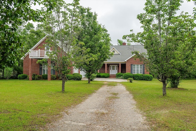 view of front of home with a chimney, brick siding, gravel driveway, and a front lawn
