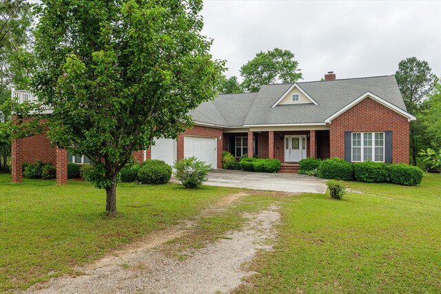 view of front of house with a front yard, a garage, brick siding, driveway, and a chimney