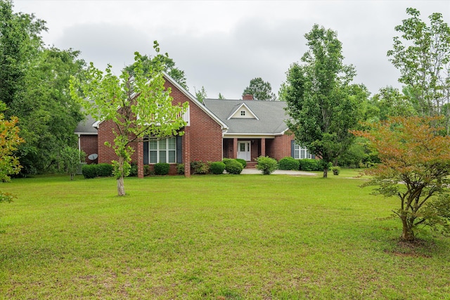 view of front of home with a chimney, a front yard, and brick siding