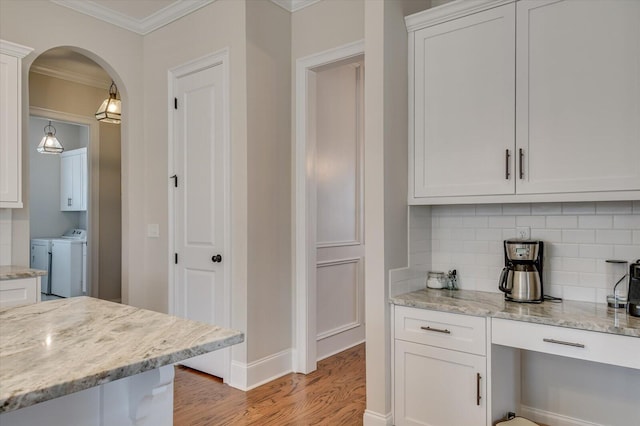 kitchen featuring light stone counters, arched walkways, crown molding, white cabinets, and light wood-type flooring