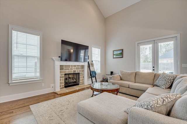 living room featuring baseboards, wood finished floors, french doors, a fireplace, and high vaulted ceiling