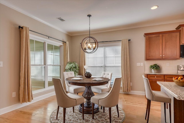 dining room with a notable chandelier, visible vents, baseboards, light wood finished floors, and crown molding