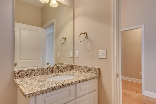 bathroom featuring baseboards, wood finished floors, and vanity