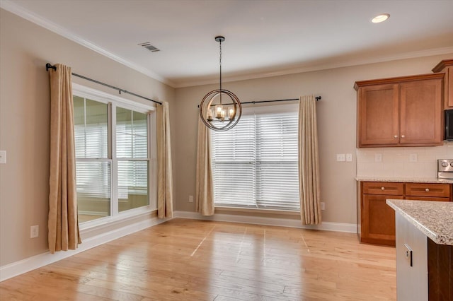 unfurnished dining area with ornamental molding, plenty of natural light, light wood-style flooring, and a notable chandelier