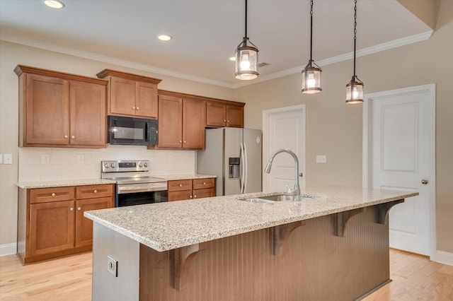 kitchen featuring light wood-style floors, appliances with stainless steel finishes, brown cabinets, and a sink