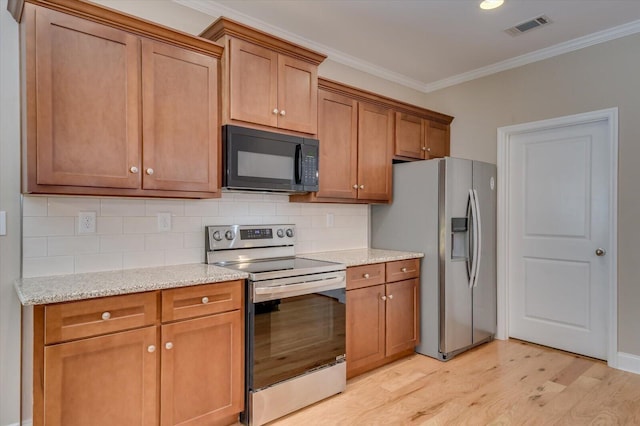 kitchen with light wood-style flooring, stainless steel appliances, visible vents, backsplash, and crown molding