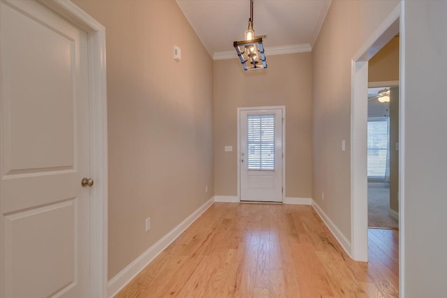 entryway with a chandelier, ornamental molding, light wood-style flooring, and baseboards