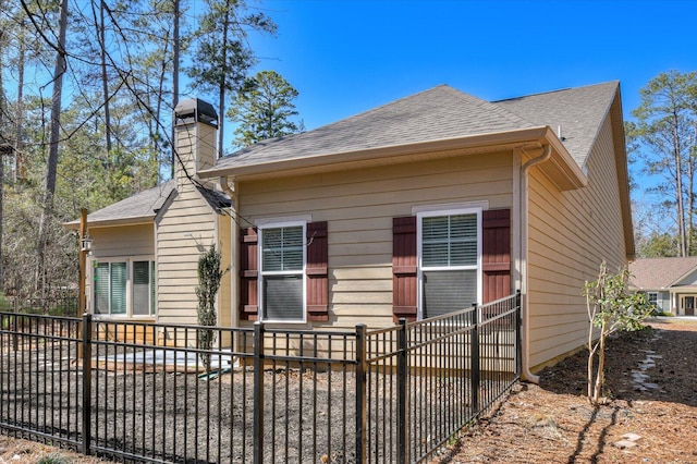 bungalow featuring a shingled roof, fence, and a chimney