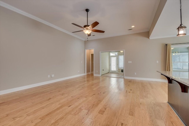 empty room featuring light wood-style flooring, visible vents, a ceiling fan, baseboards, and ornamental molding