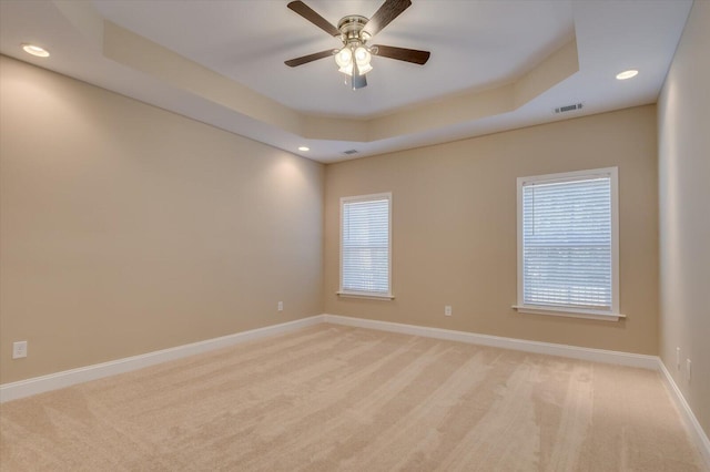 unfurnished room with recessed lighting, light colored carpet, visible vents, baseboards, and a tray ceiling