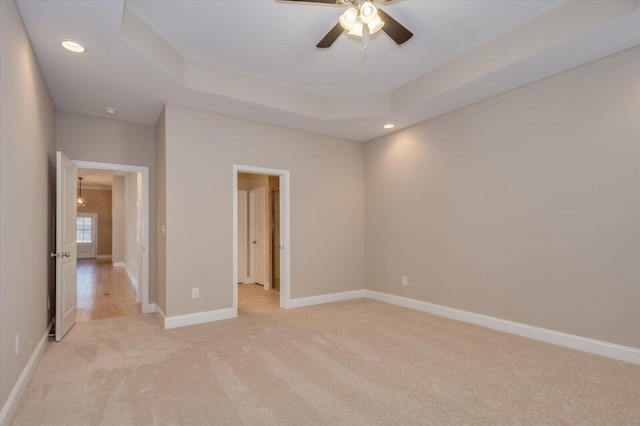 unfurnished bedroom featuring baseboards, a raised ceiling, light colored carpet, ceiling fan, and recessed lighting