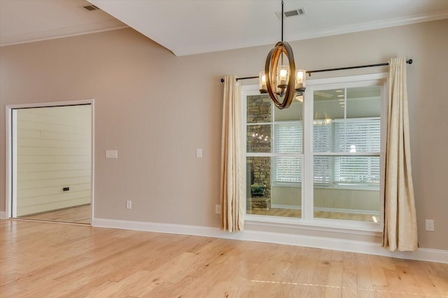 empty room featuring visible vents, ornamental molding, a chandelier, light wood-type flooring, and baseboards