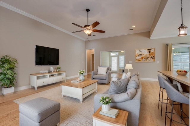 living room featuring ornamental molding, light wood-type flooring, ceiling fan, and baseboards