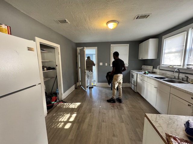 2021 Ellis St, Augusta, GA 30904 - kitchen with white appliances, wood finished floors, light countertops, white cabinets, and a textured ceiling