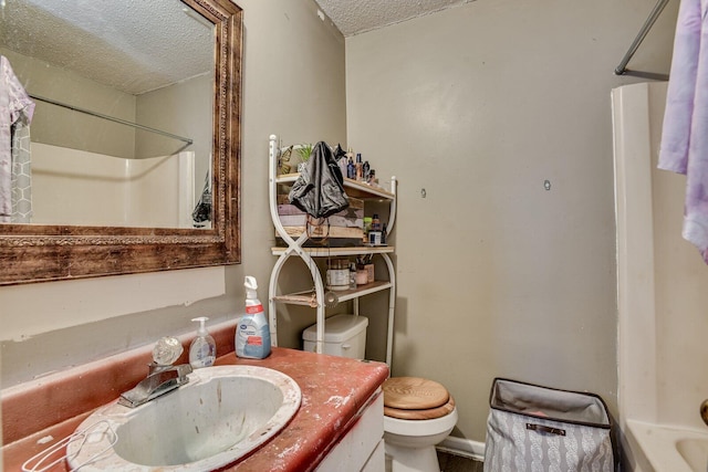 full bathroom featuring a textured ceiling, washtub / shower combination, vanity, and toilet