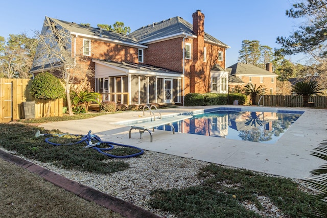 view of pool featuring a diving board, a patio area, and a sunroom