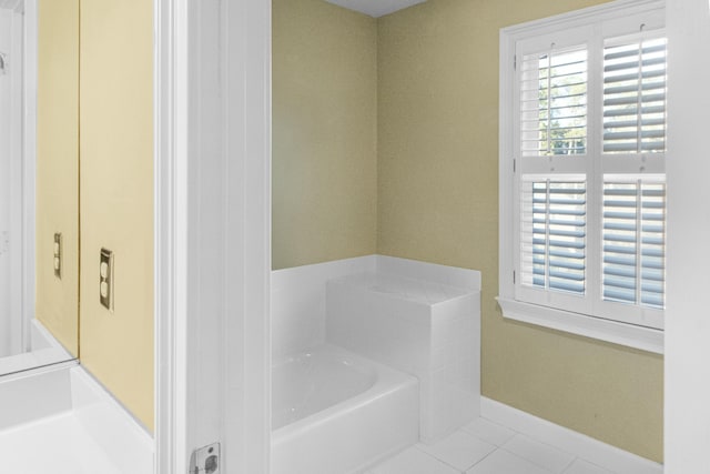 bathroom with tile patterned floors and a bath