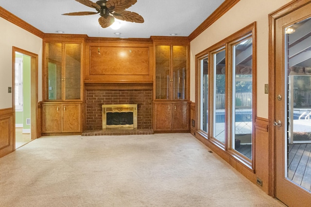 unfurnished living room with ceiling fan, a fireplace, light colored carpet, and ornamental molding