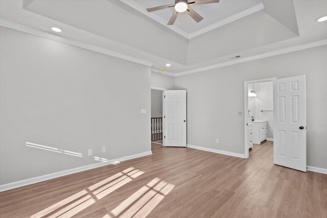 unfurnished bedroom featuring a tray ceiling, ensuite bathroom, ceiling fan, and ornamental molding