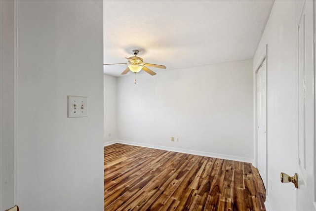 empty room with a ceiling fan, dark wood-style floors, and baseboards