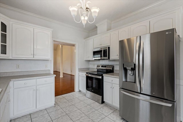 kitchen featuring stainless steel appliances, white cabinets, a chandelier, ornamental molding, and glass insert cabinets